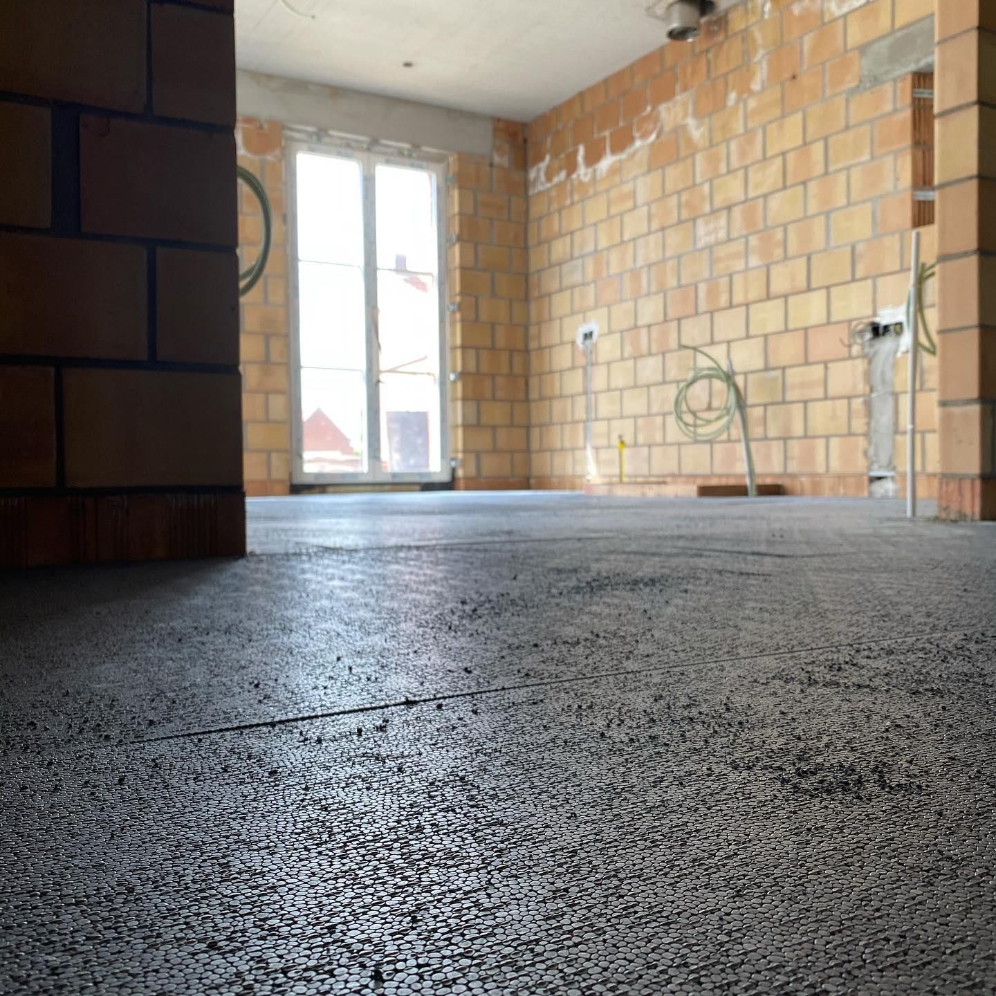 Vloerisolatie in nieuwbouw met bakstenen muren en ramen, energie-efficiëntie voor wooncomfort en warmtebehoud.