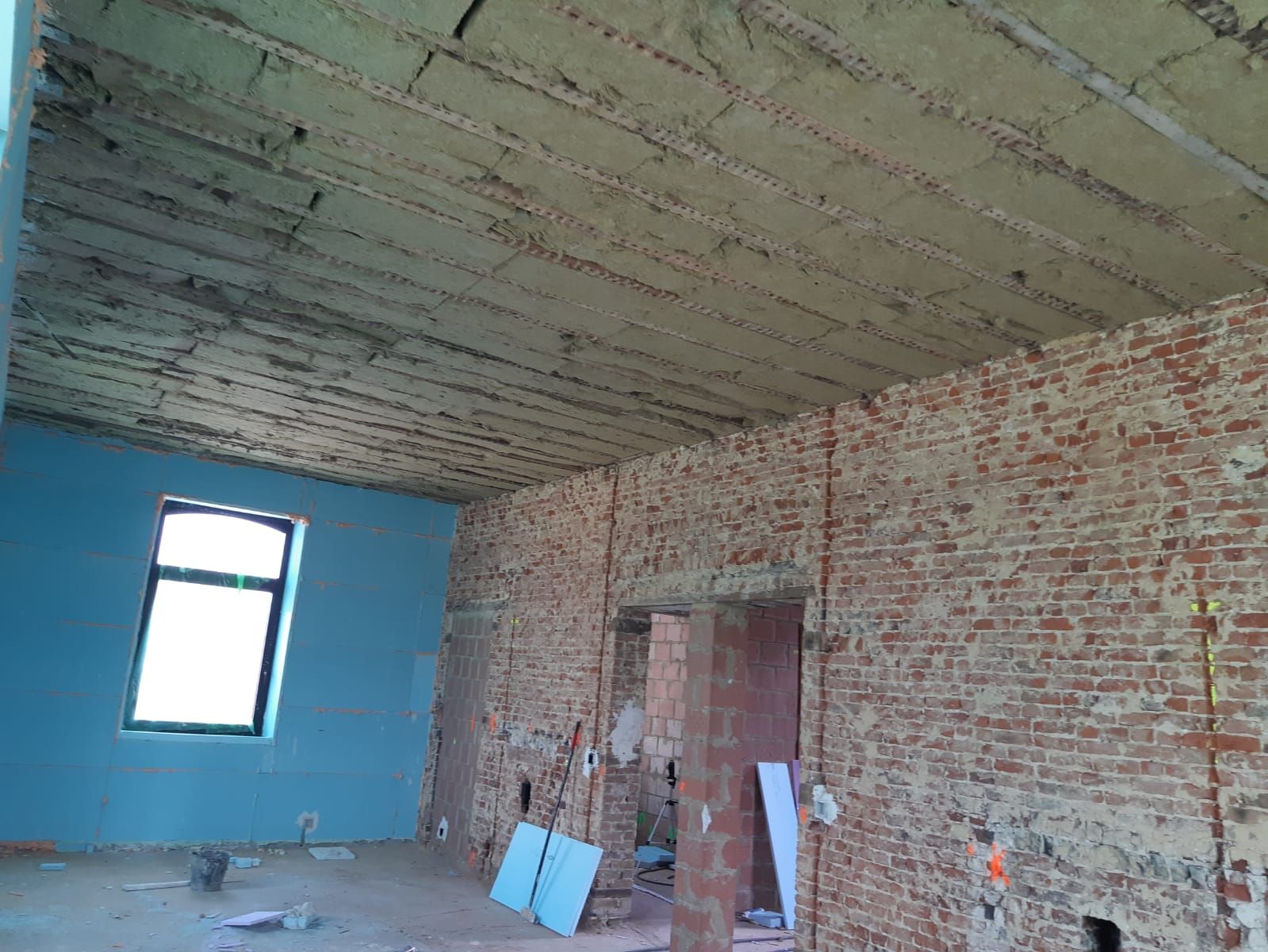 Renovatie van industrieel interieur met bakstenen muren en plafondisolatie, gericht op energiezuinige opknapbeurt en warmtebehoud.