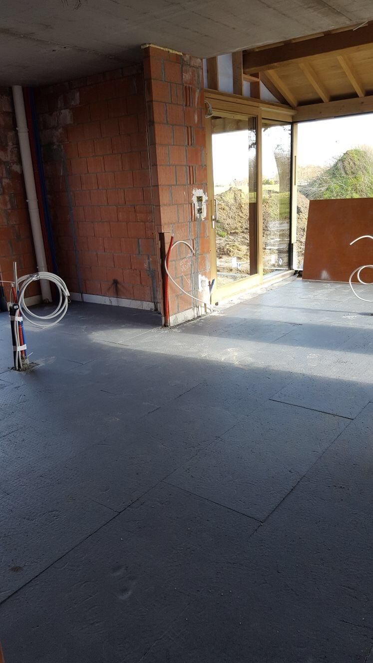 Interieur van nieuwbouw met bakstenen muren, leidingen en glazen deur naar buiten.